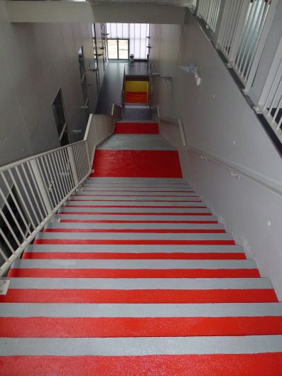 Des escaliers avec marches et nez-de-marches de couleurs différentes pour un meilleur contraste visuel et une accessibilité améliorée.